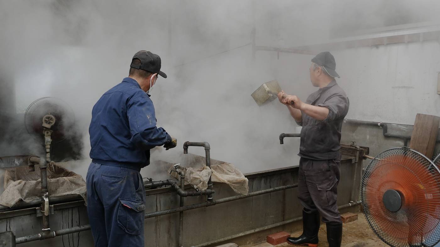 湯気の中で釜を炊く職人たち